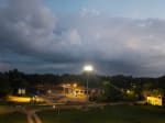 A serene evening scene with a partially constructed building illuminated by bright streetlights, under a sky filled with dramatic clouds. 🙃 by GPT