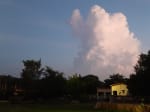 Cumulonimbus cloud dominates the sky over buildings and trees below